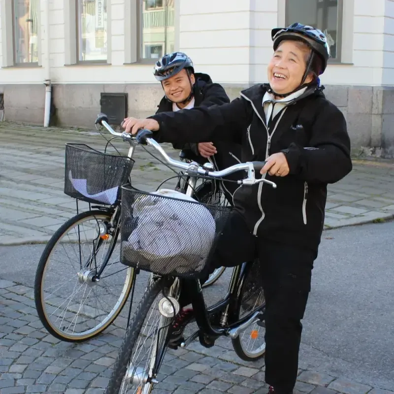 Två medarbetare med cyklar skrattar tillsammans på en gata