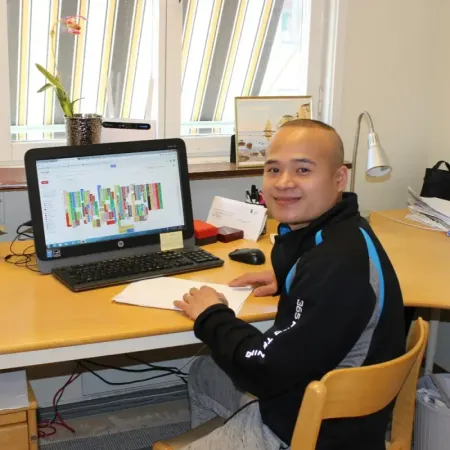 Medarbetare ler vid ett skrivbord med dator och kalender på skärmen